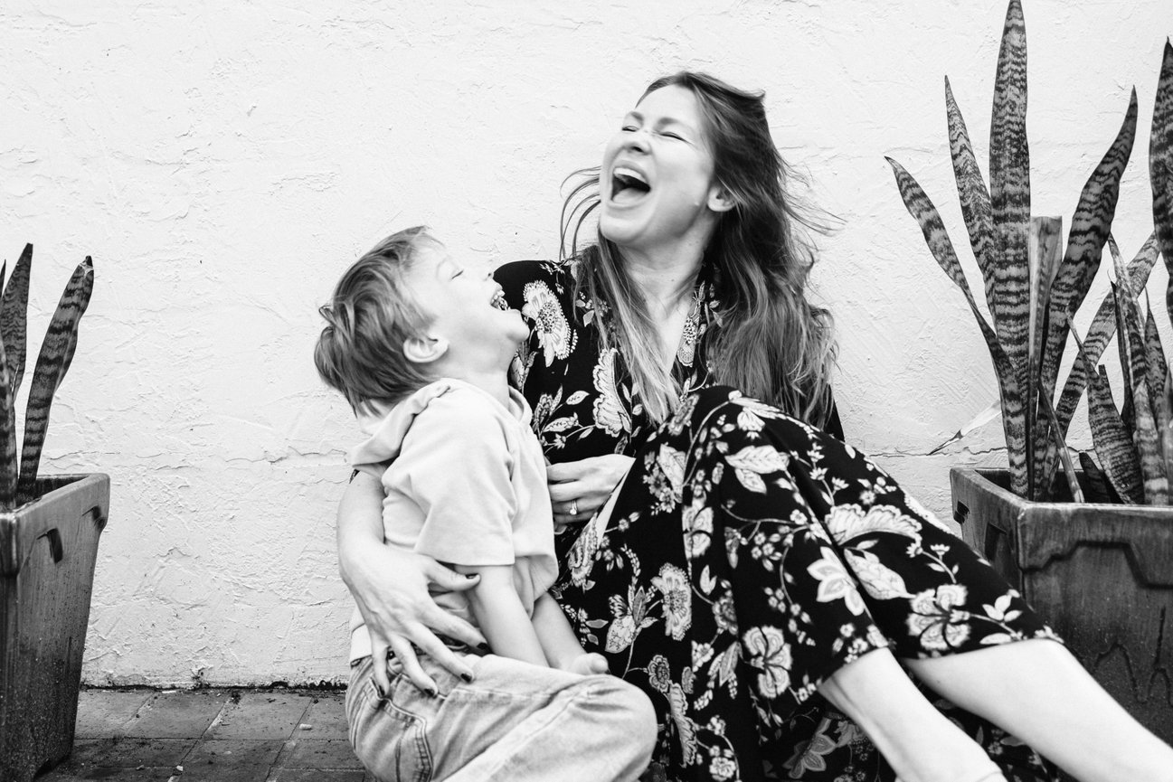 during a mommy and me family photo session in Virginia a mom hugs her side, laughs with eyes closed, and sings loudly