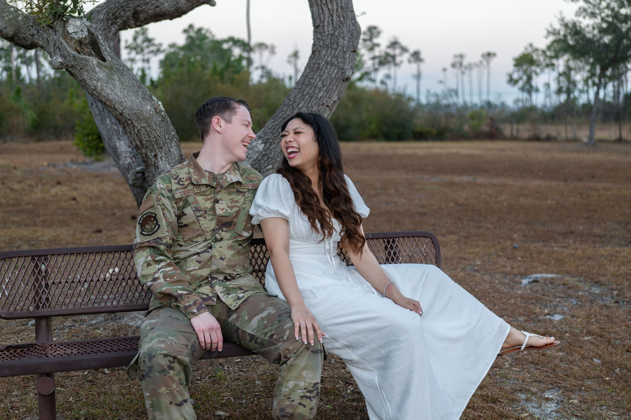 Military couple laughing on a park bench