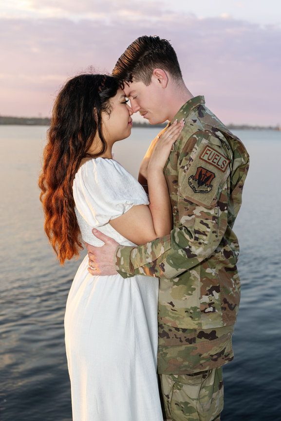 Military couple embracing by the water at sunset