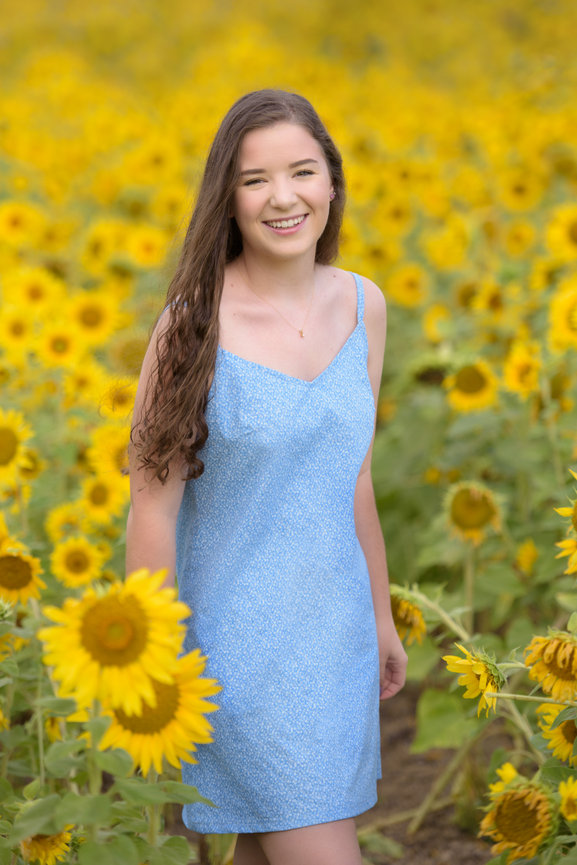 Senior standing in a sunflower field in a blue dress
