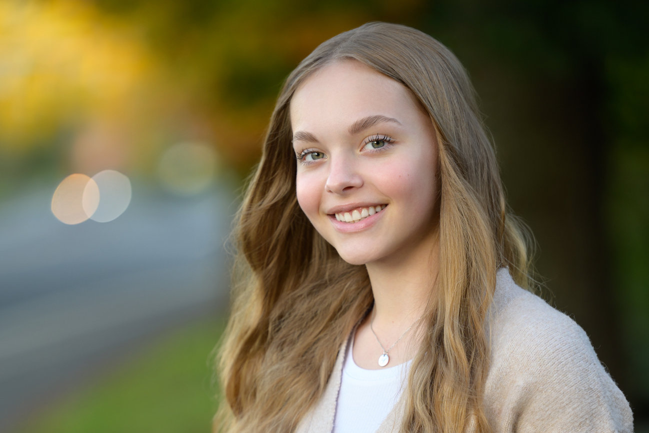 senior girl along a roadside with blurred bokeh