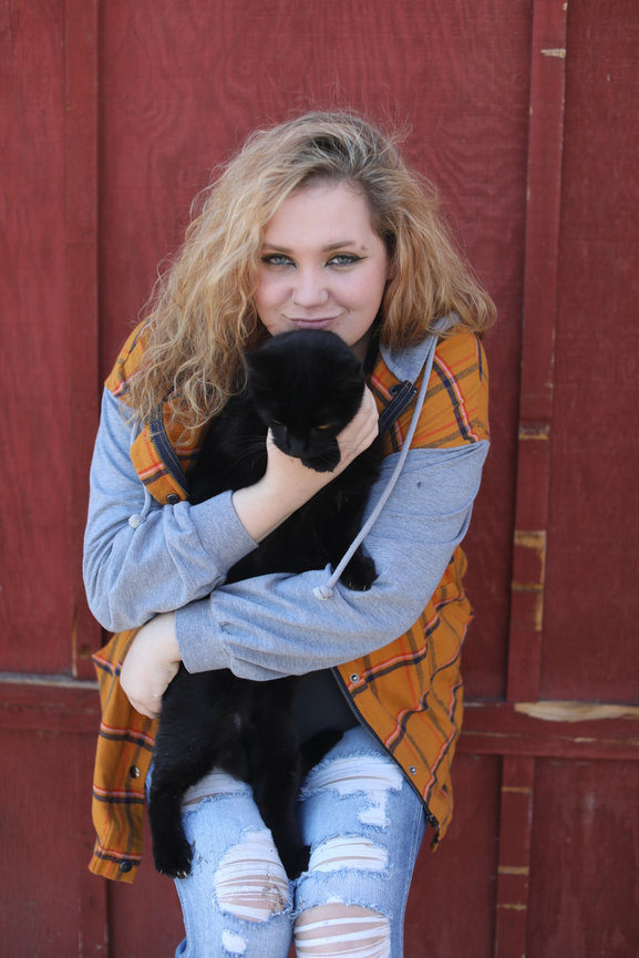 High school senior young woman with her beloved pet cat in front of a rustic barn. Captured with warm, natural light to reflect connection, authenticity, and timeless charm. Luxury senior portrait experience for Colorado’s discerning families.