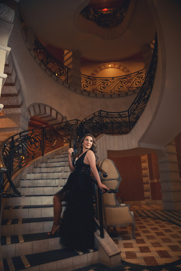 Beautiful picture taken of woman in black dress and dramatic spiral staircase with professional lighting. Professional picture taken by Adam Trujillo, a Las Vegas studio portrait photographer.