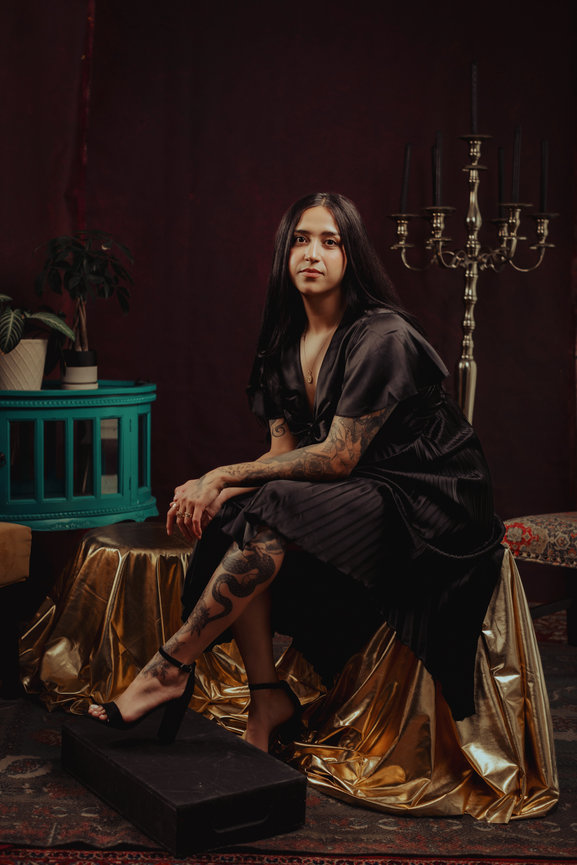 Fancy set design in studio for a professional portrait photosdhoot of woman in black dress and deep red backdrop, taken in a photo studio with Adam Trujillo, a Las Vegas portrait photographer.