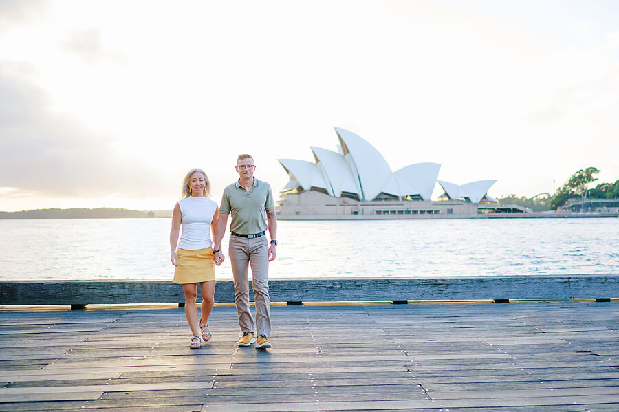 A Sydney Opera House photoshoot with a couple walking holding hands beside the harbour.