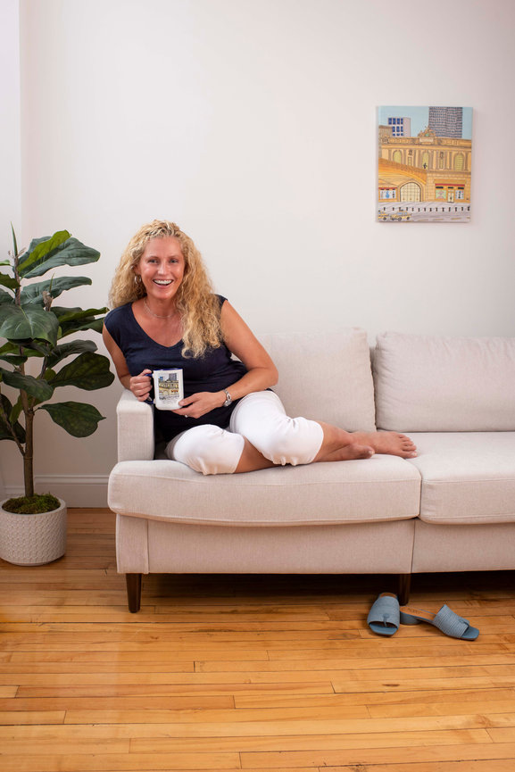 Woman laughing while sitting on a couch holding a mug