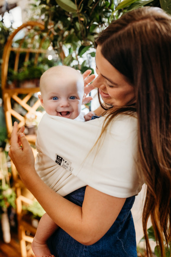 Woman holding baby in baby carrier in Huntsville Alabama greenhouse