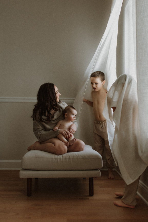 A mother playing hide and seek with her two sons during an in home photography session in New Jersey.