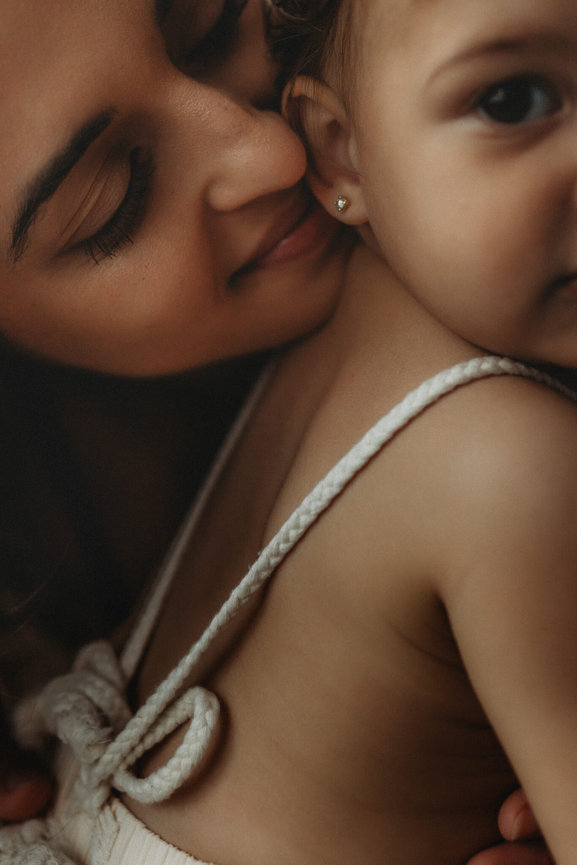 A close up of a mother whispering in her baby's ear during a motherhood and baby photography session in New Jersey.
