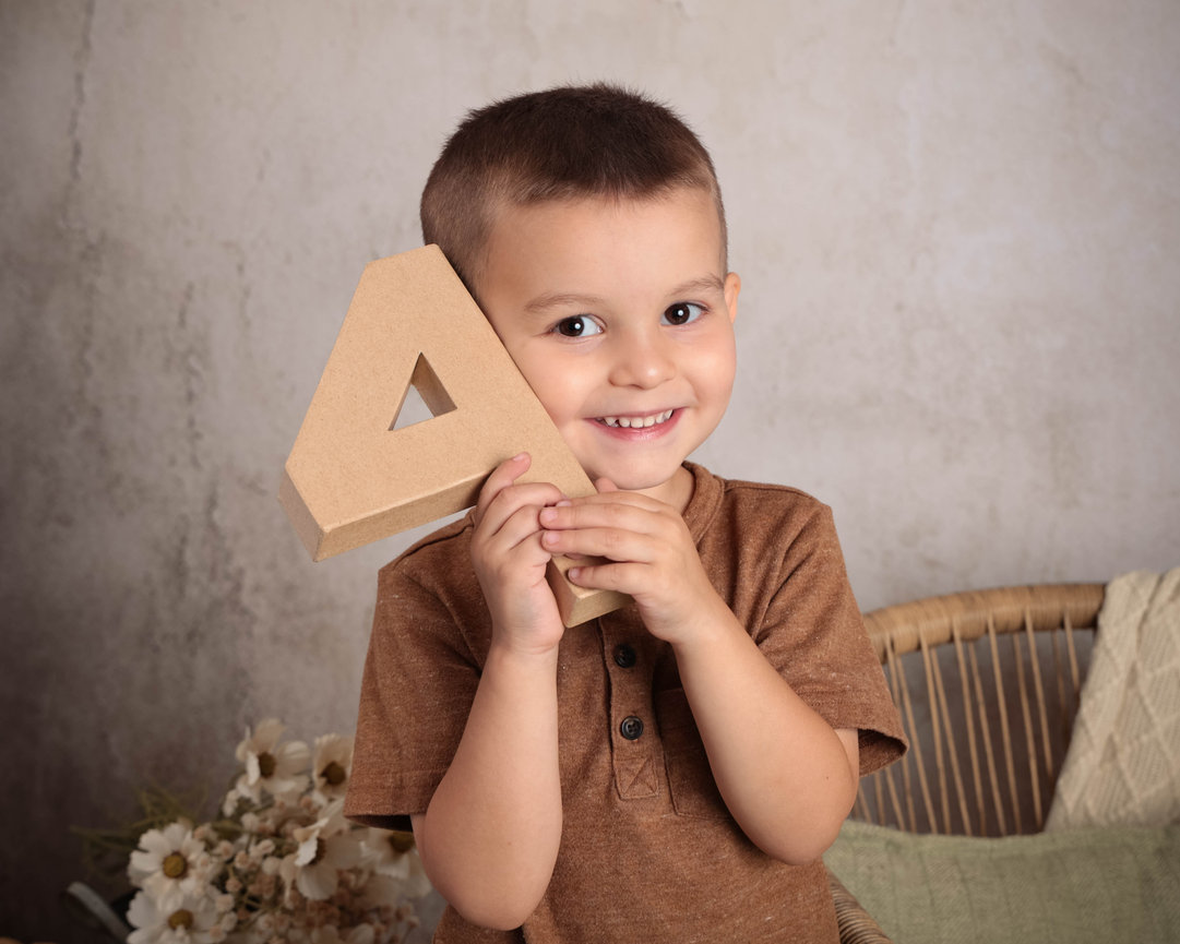 Smiling baby lying on a shaggy carpet holding a wooden sign reading Six Months.