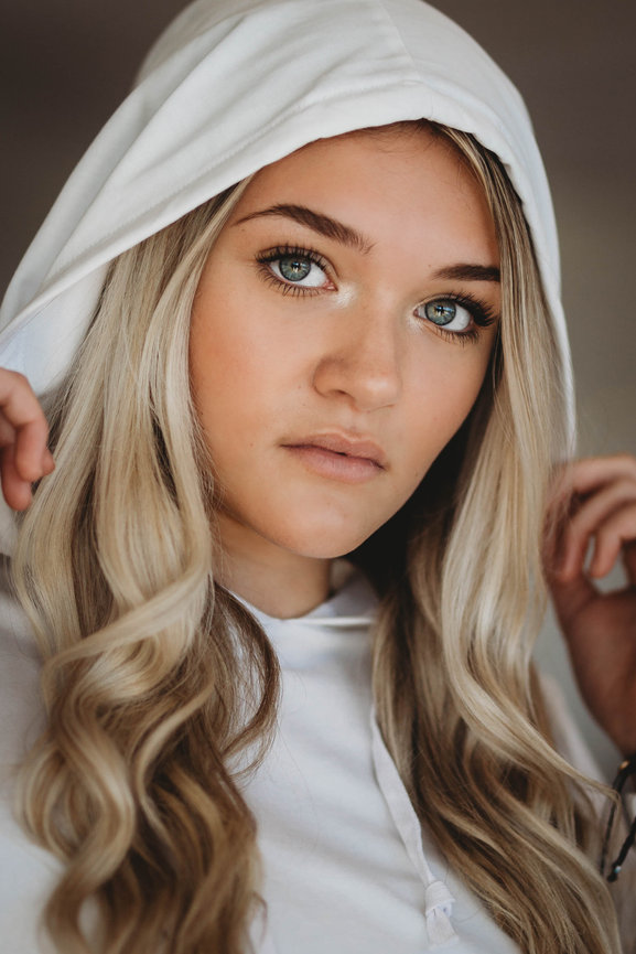 Portrait of a blonde high school senior girl with a white hoodie on
