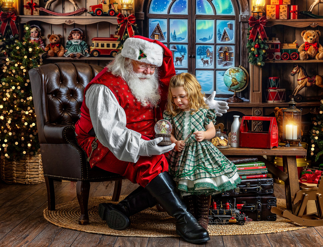 Santa Claus showing a little girl a magical snowglobe inside Santa's Workshop set during a Christmas mini session in Wooster, Ohio.