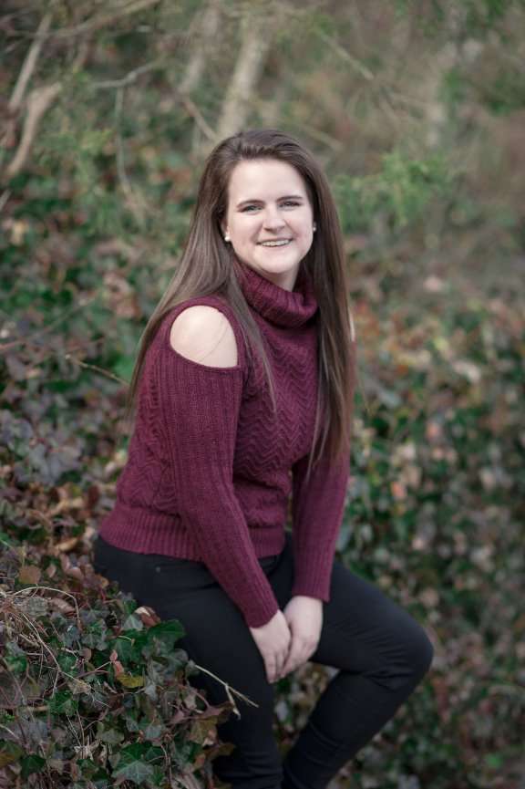 senior girl sitting on ivy covered wall posing for portraits at Dogwood Canyon