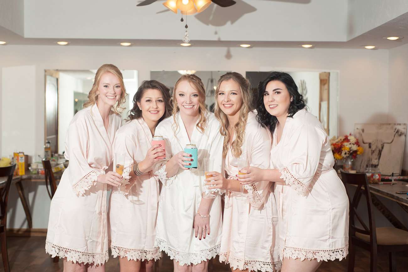 Bride with bridesmaids in robes with drinks before wedding.