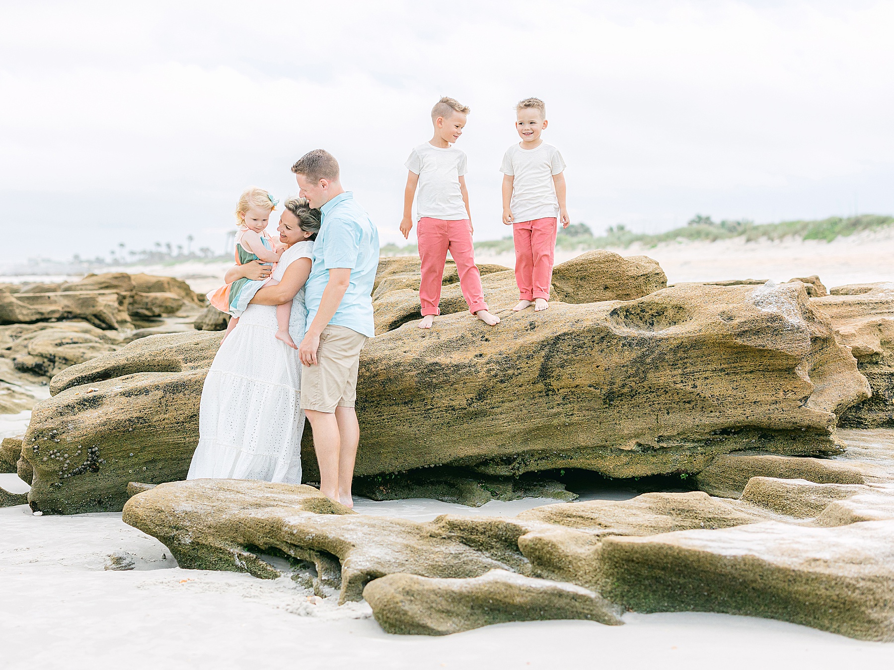 family standing on the beach in pastel colors