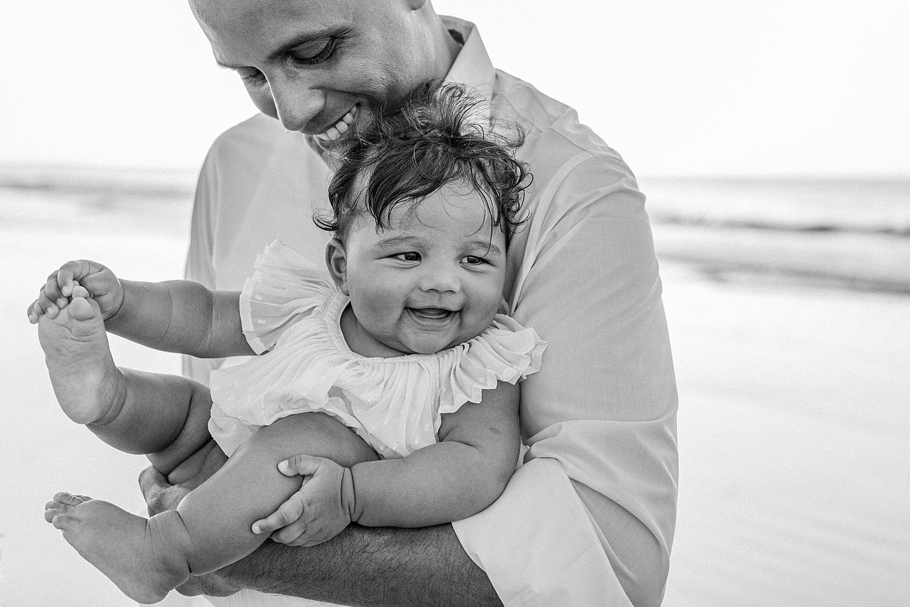 black and white image of man holding baby girl in white dress