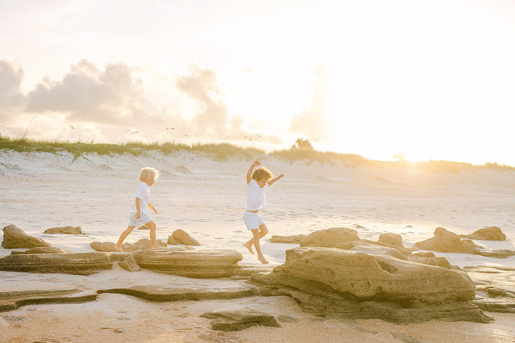 children chasing each other on the beach at sunset