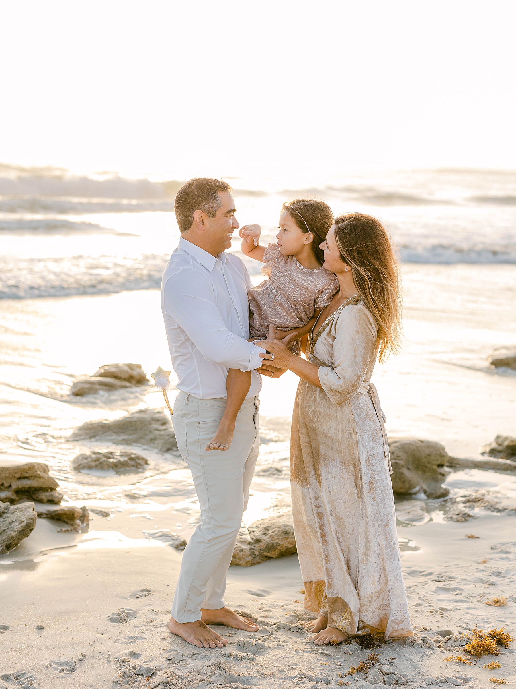family standing on the beach at sunrise wearing metallic shimmery clothing