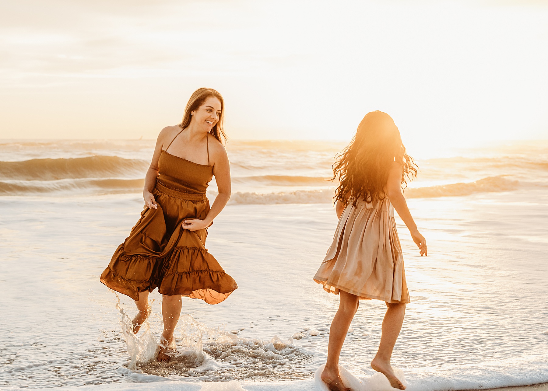 woman running with little girl at sunrise on the beach