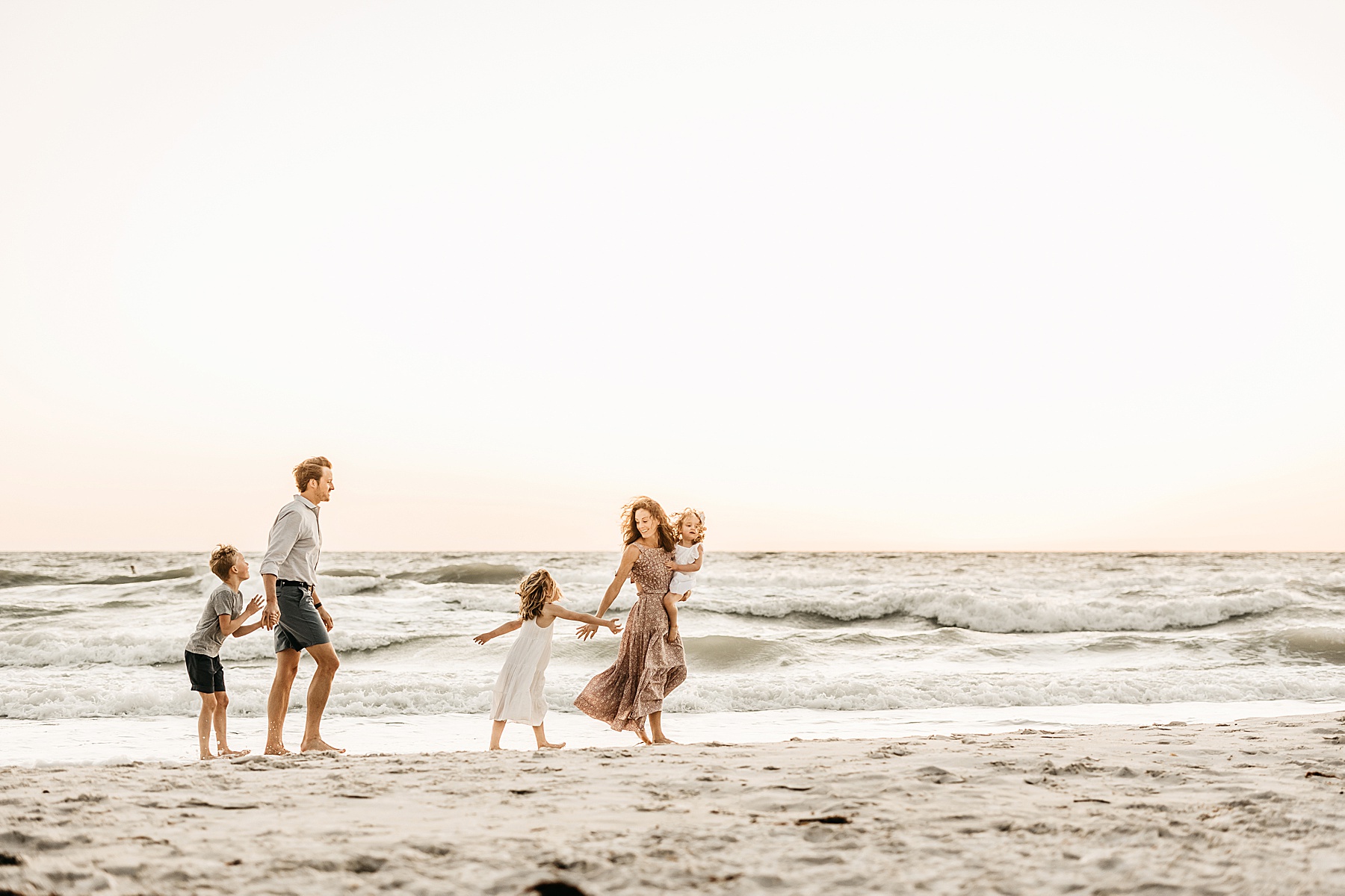 family walking on the beach at wiggins pass at sunset