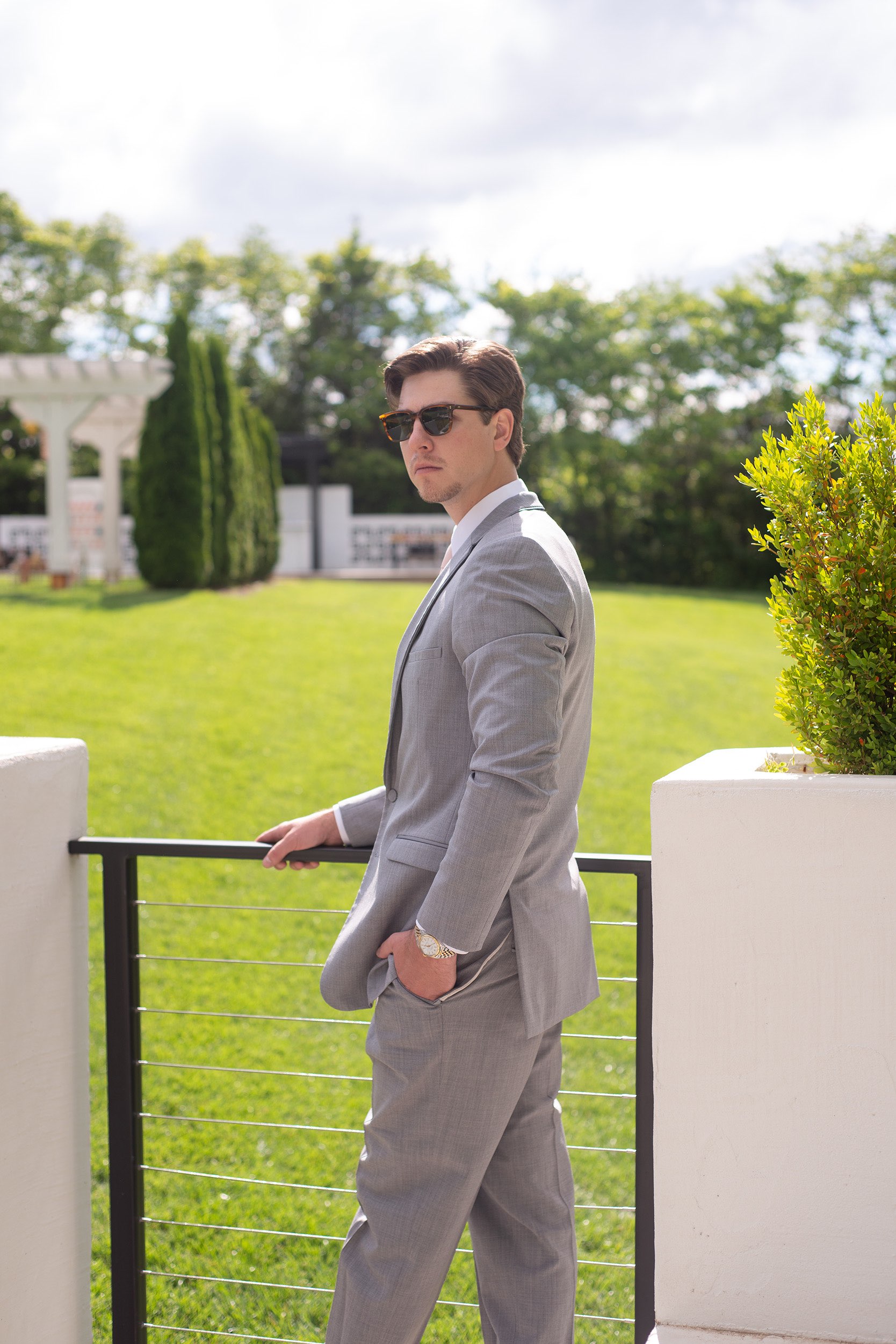 Groom with sunglasses standing on deck near Greenhouse Two Rivers.