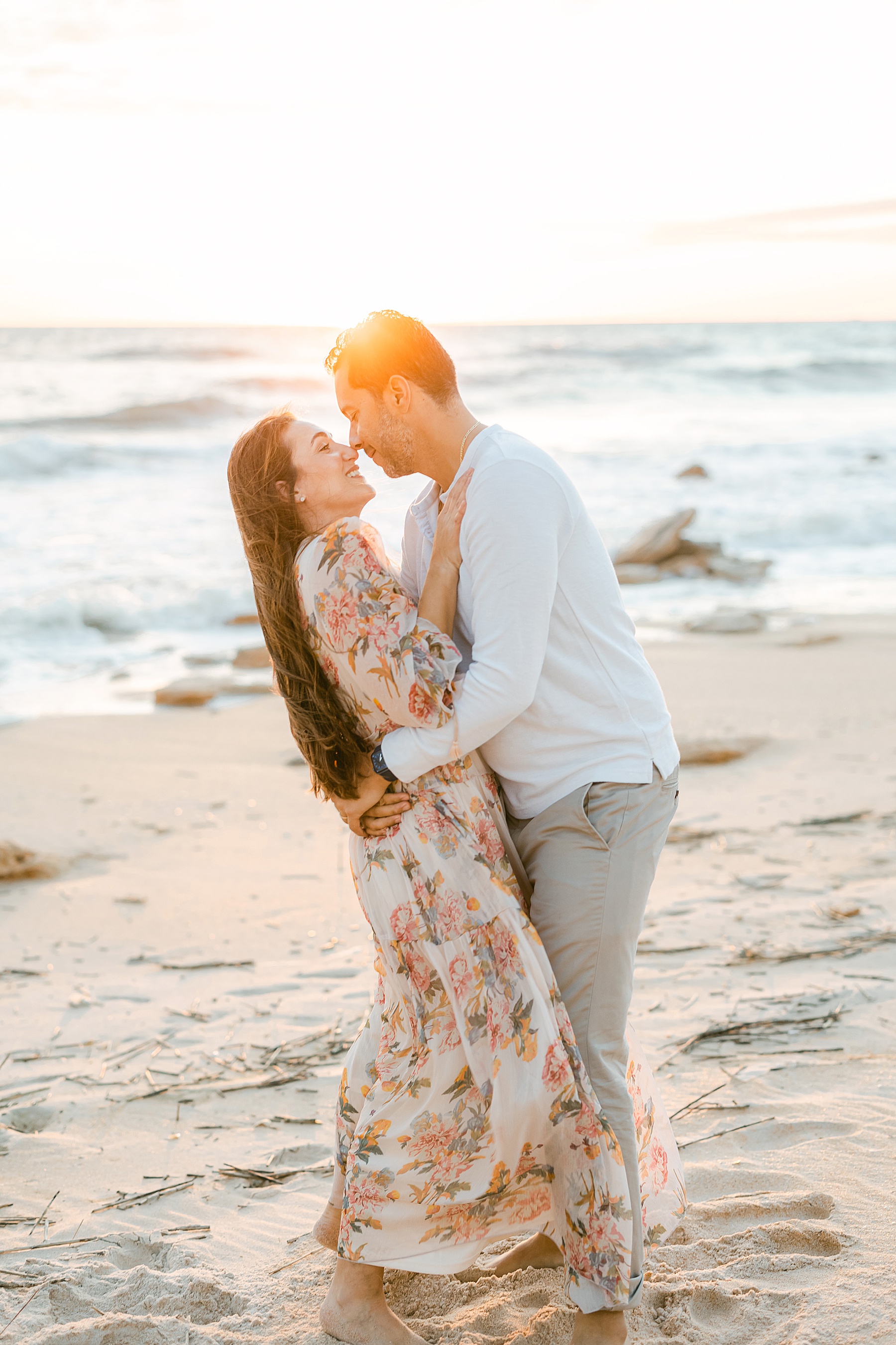 man and woman holding each other on the beach at sunrise