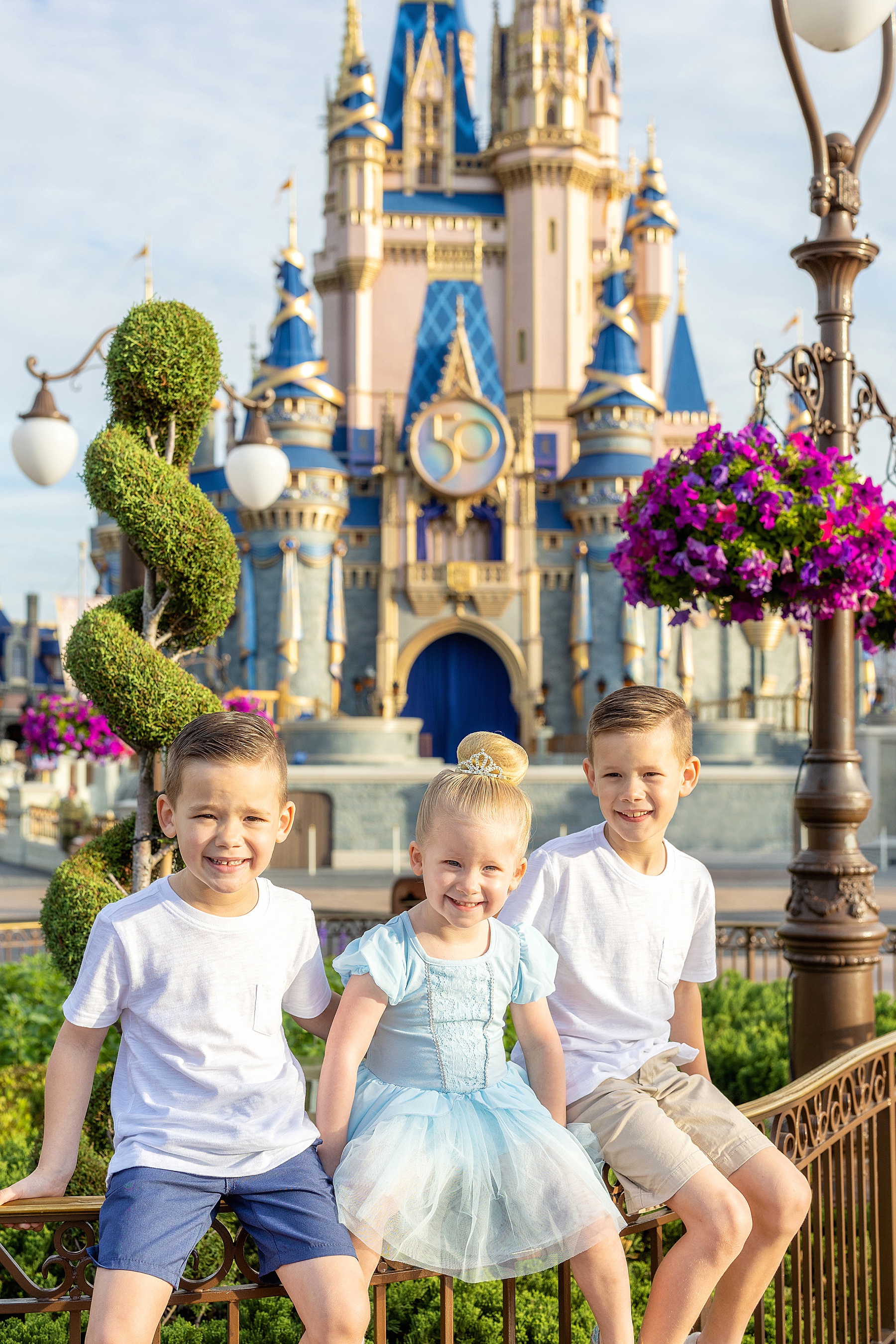 siblings sitting on fence in front of Magic Kingdom Castle Walt Disney World
