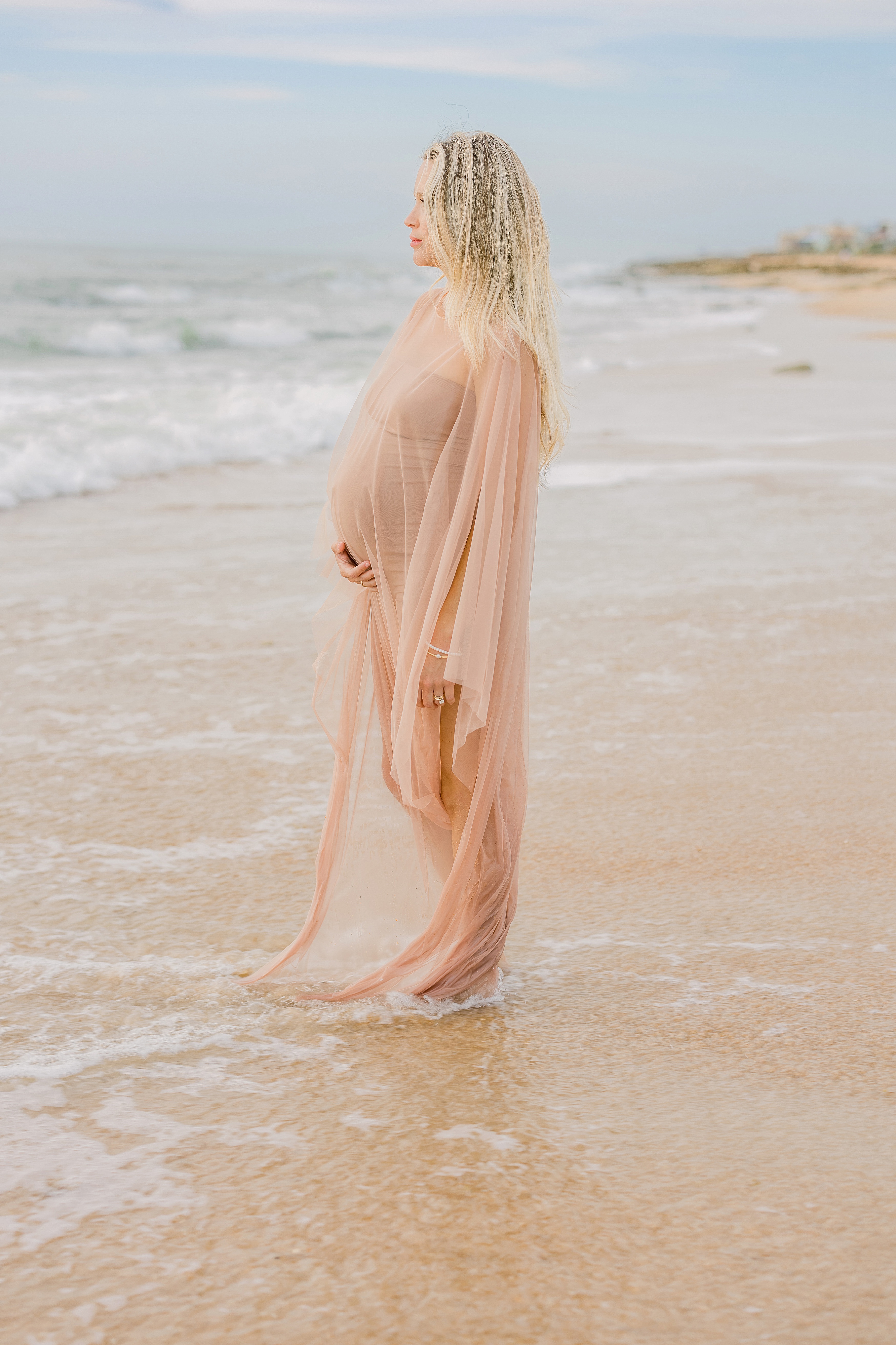 pregnant woman in light and airy clothing at the beach at sunrise in Florida
