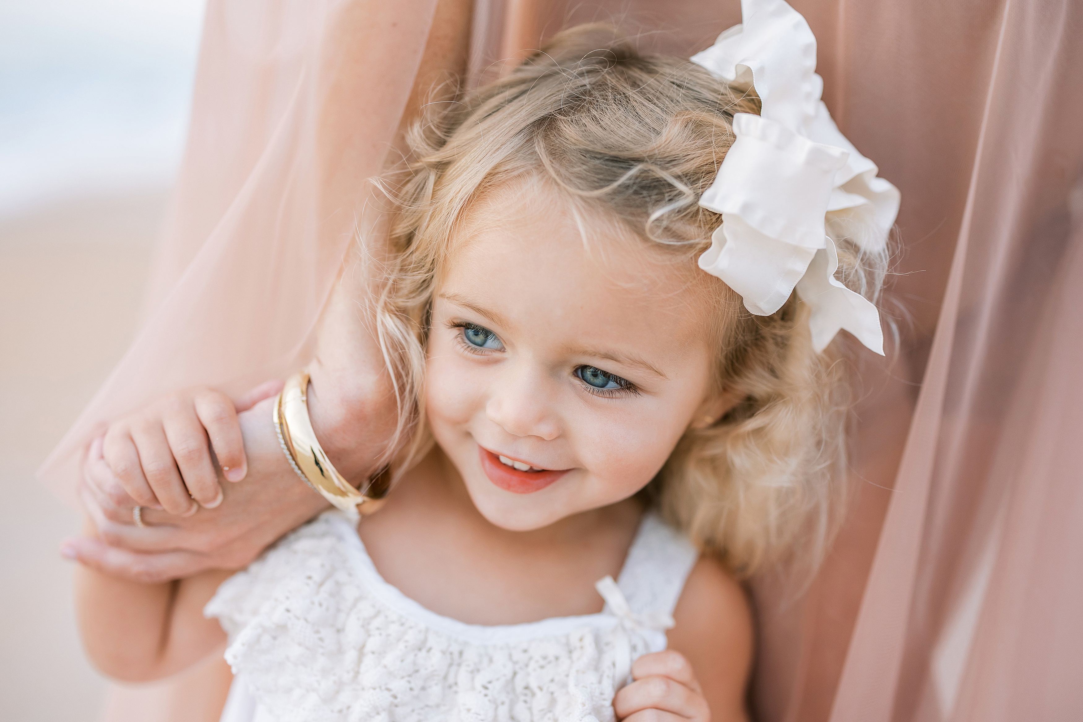 little blonde girl with gold bracelet and white dress on the beach at sunrise