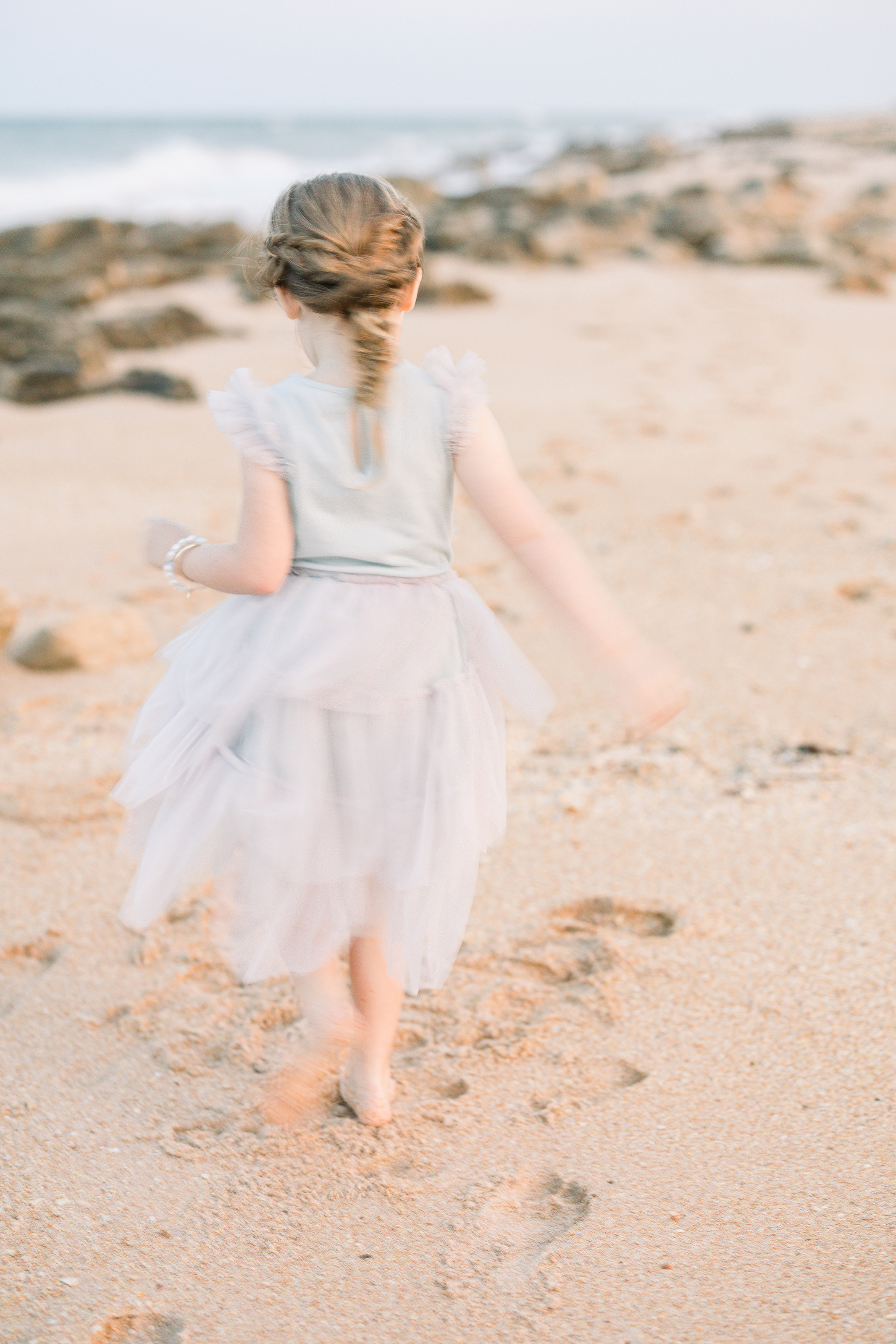little girl in lilac tulle dress running in the sand in Saint Augustine Beach