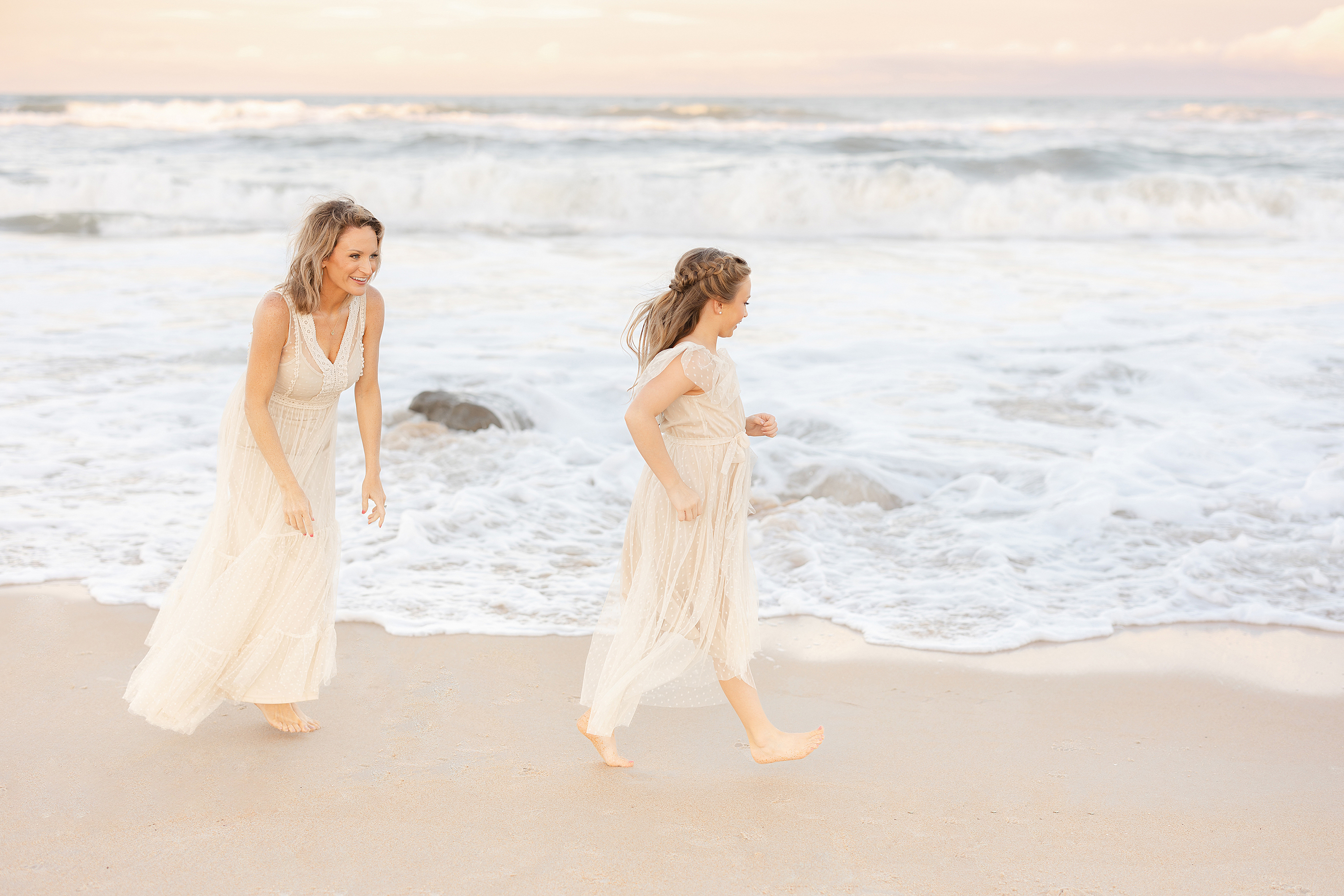 A woman plays in the surf with her daughter at the beach.