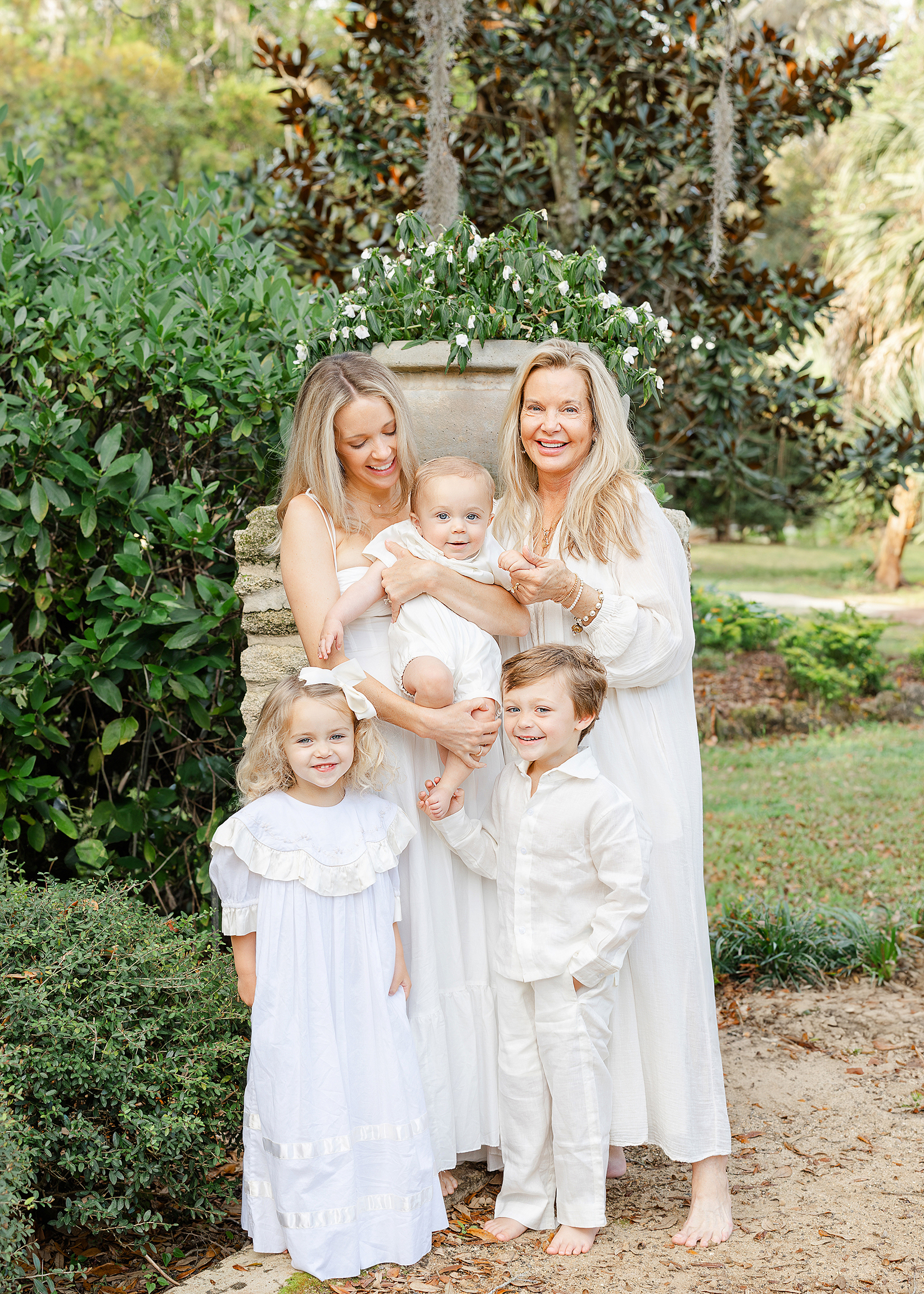 A family portait of five all dressed in white in the gardens at Washington Oaks State Park.