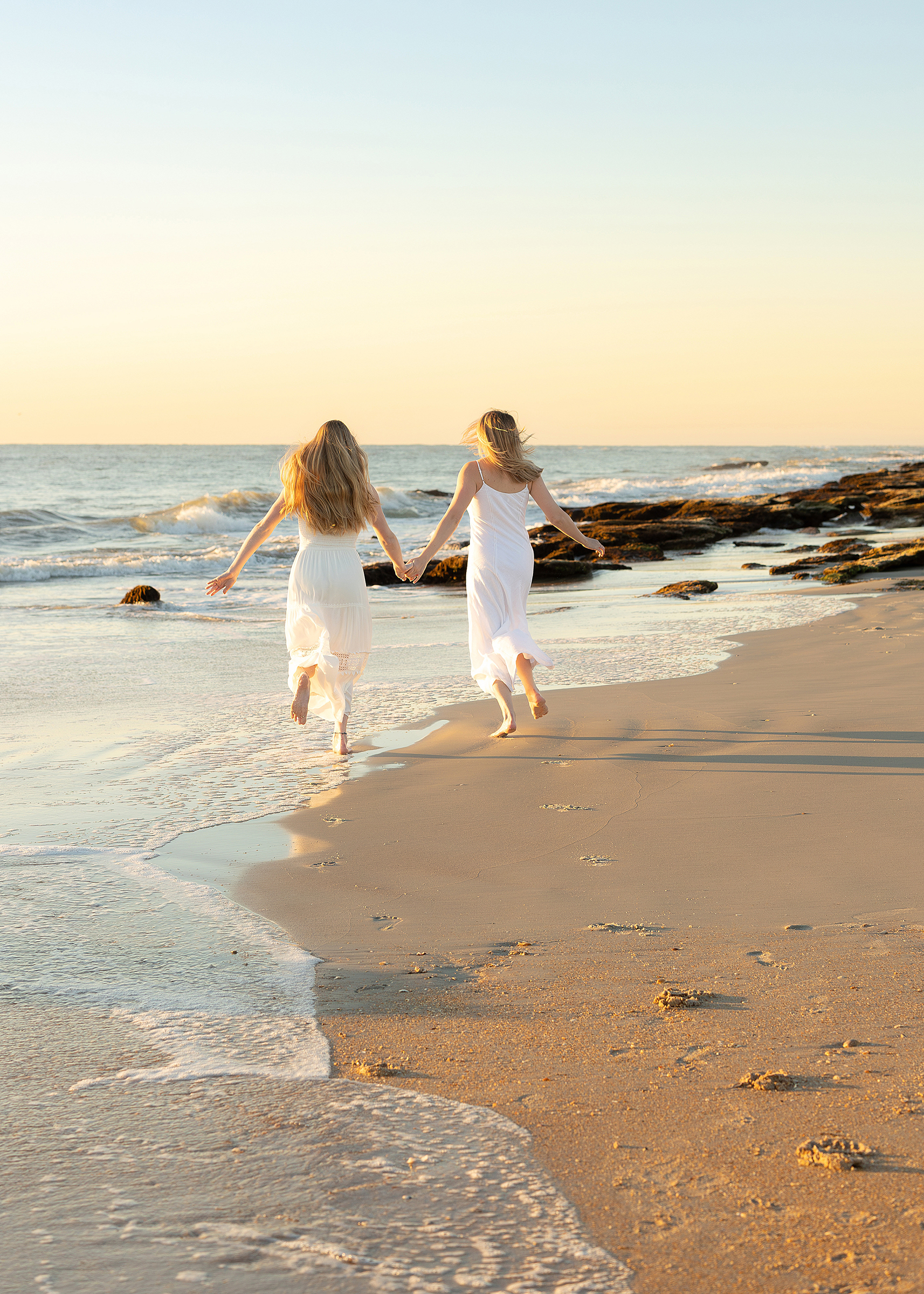 Two woman run down the beach at sunrise in Saint Augustine.