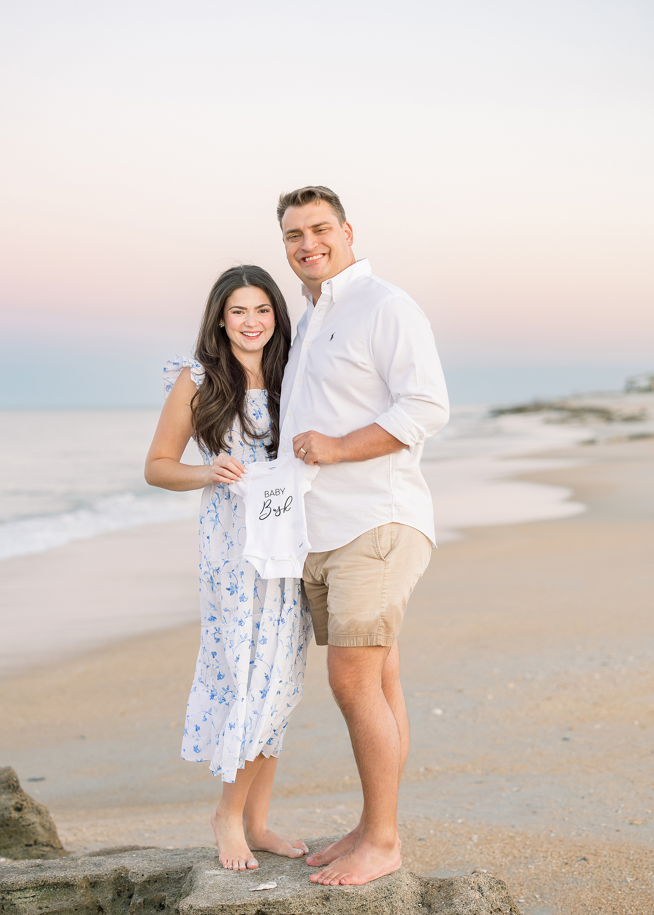 A pregnancy announcement portrait of a couple on St. Augustine Beach at sunset.