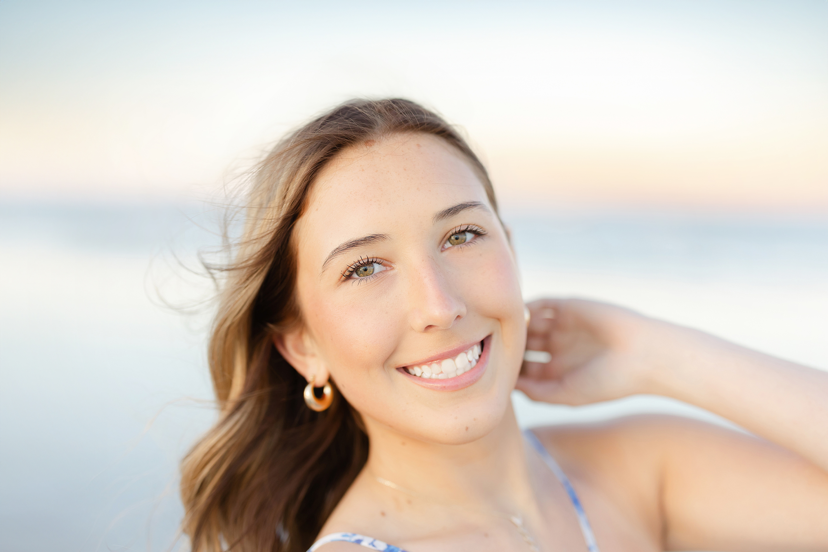 A beach portrait of a young woman in a blue and white floral dress at sunset on St. Augustine Beach..