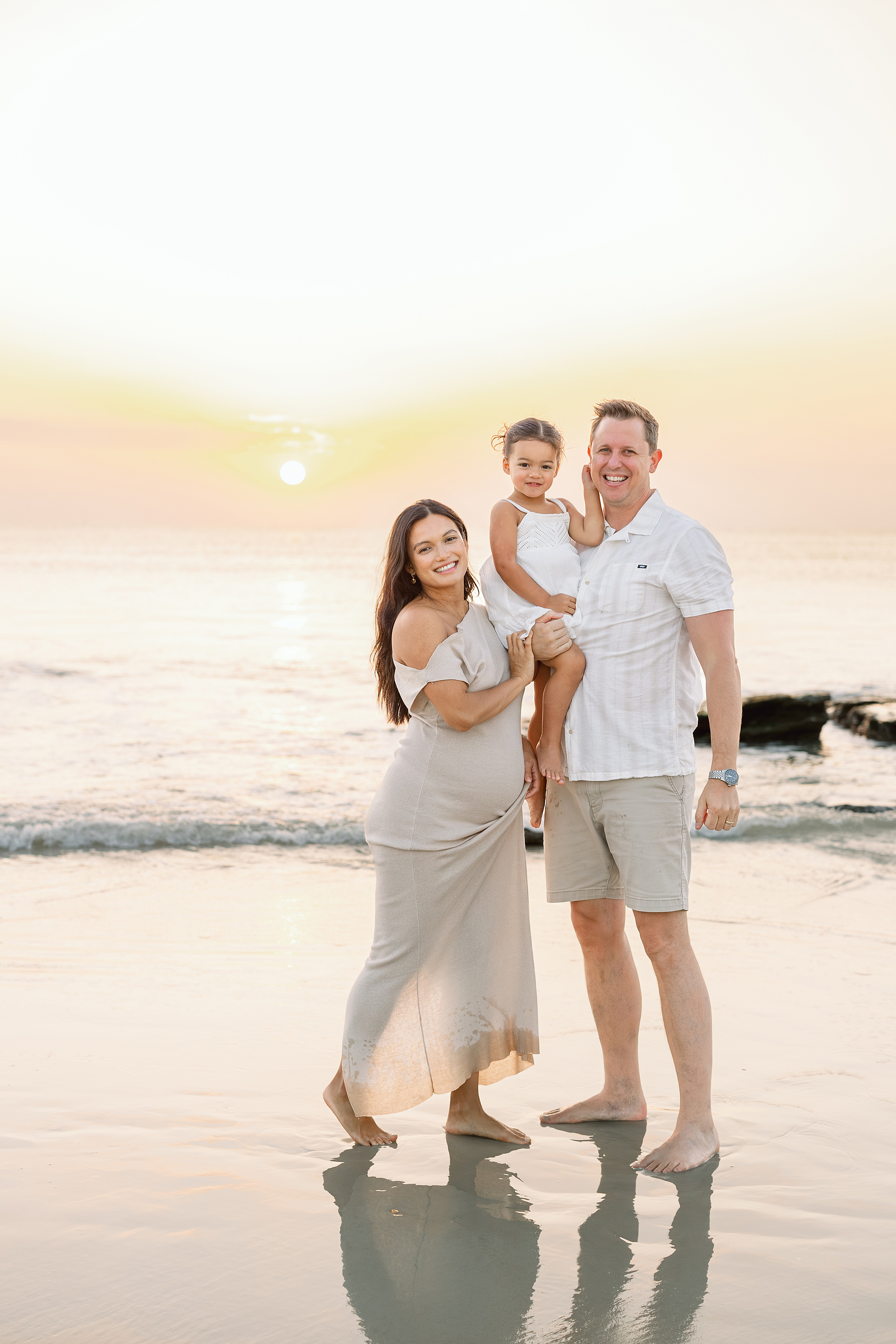 A sunrise family portrait of a family of three on St. Augustine Beach at sunrise.