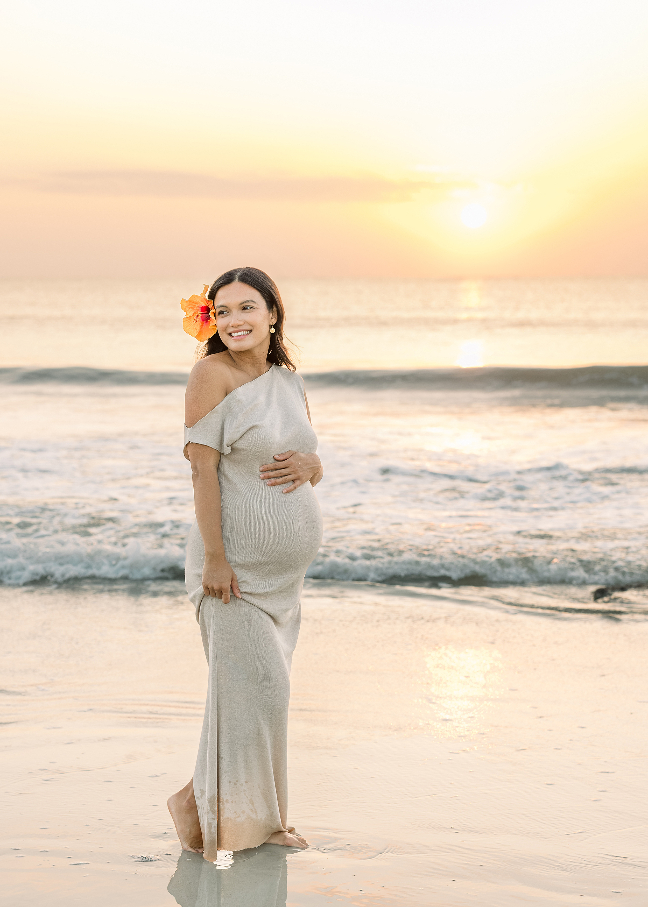 A happy and colorful sunrise pregnancy portrait of a woman on the beach.