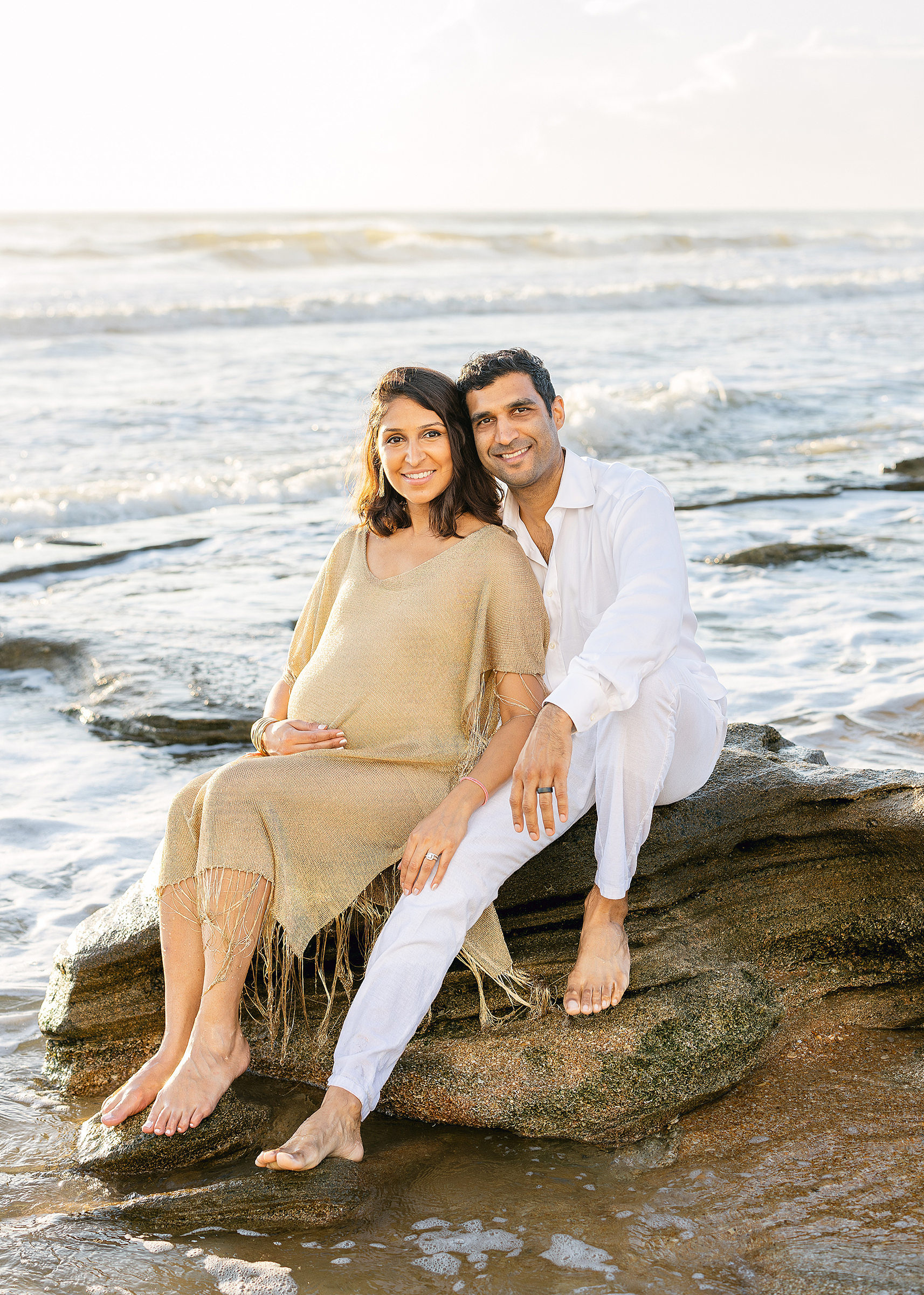 A man and a woman sit on the rocks in Saint Augustine Beach, Florida at sunrise.