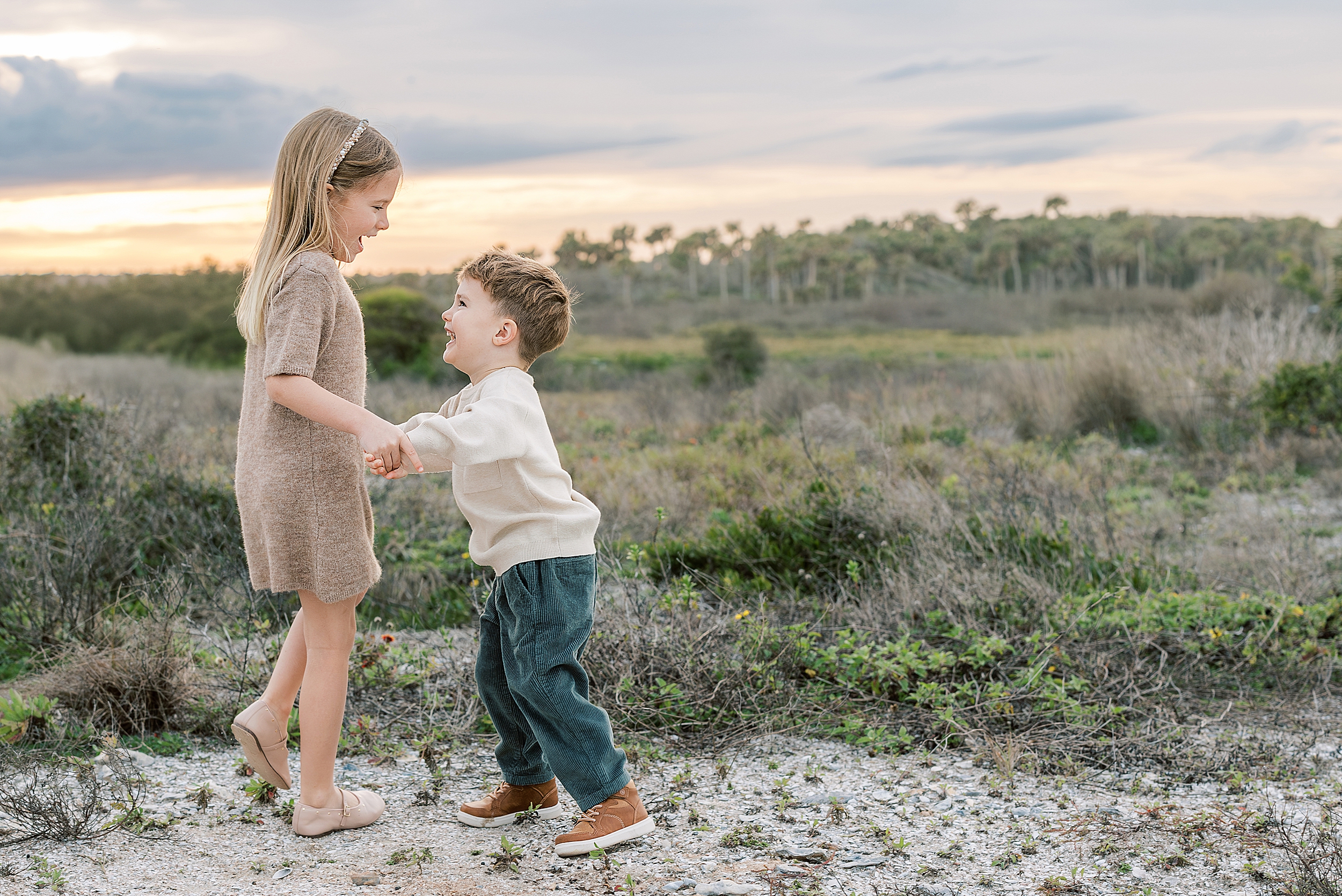 Two little children dance together during a family portrait session.