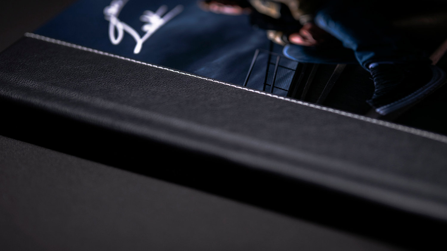 Close-up of a black leather-bound photo album with a partially visible image and stitched edge.