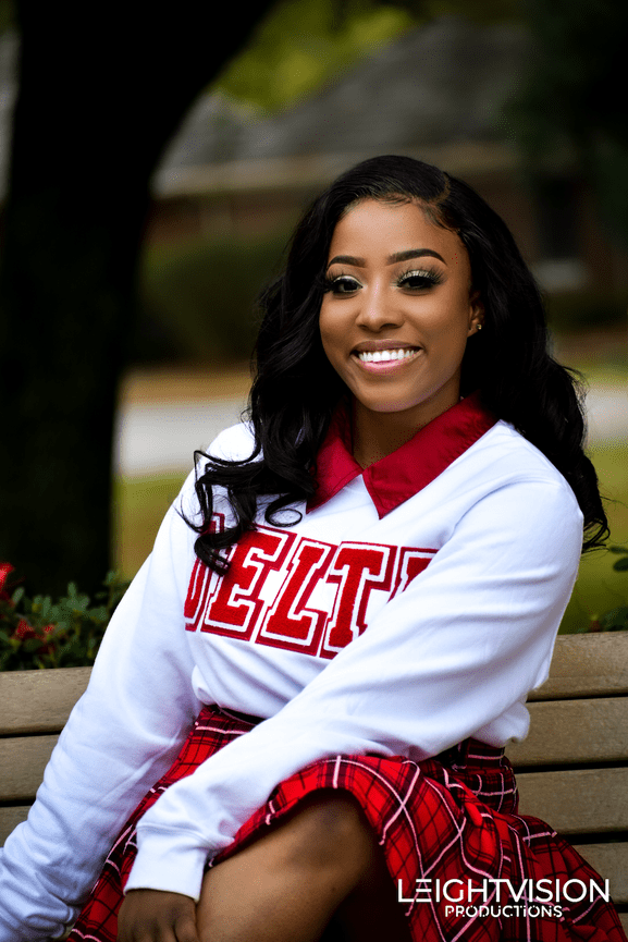 A young woman dressed in a red plaid skirt and white shirt sits comfortably on a bench, surrounded by a serene environment.