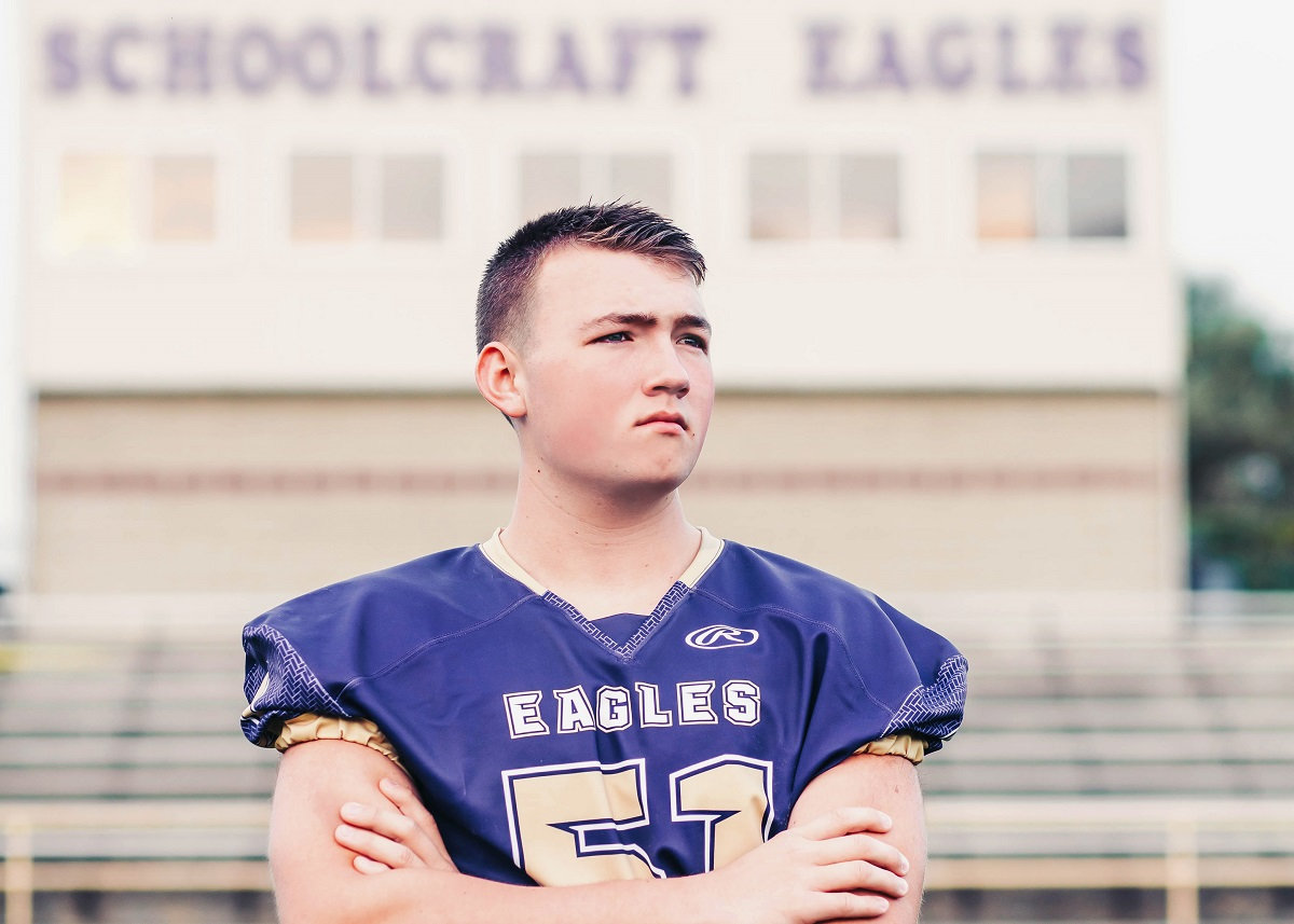 Schoolcraft High school football player in front of stadium
