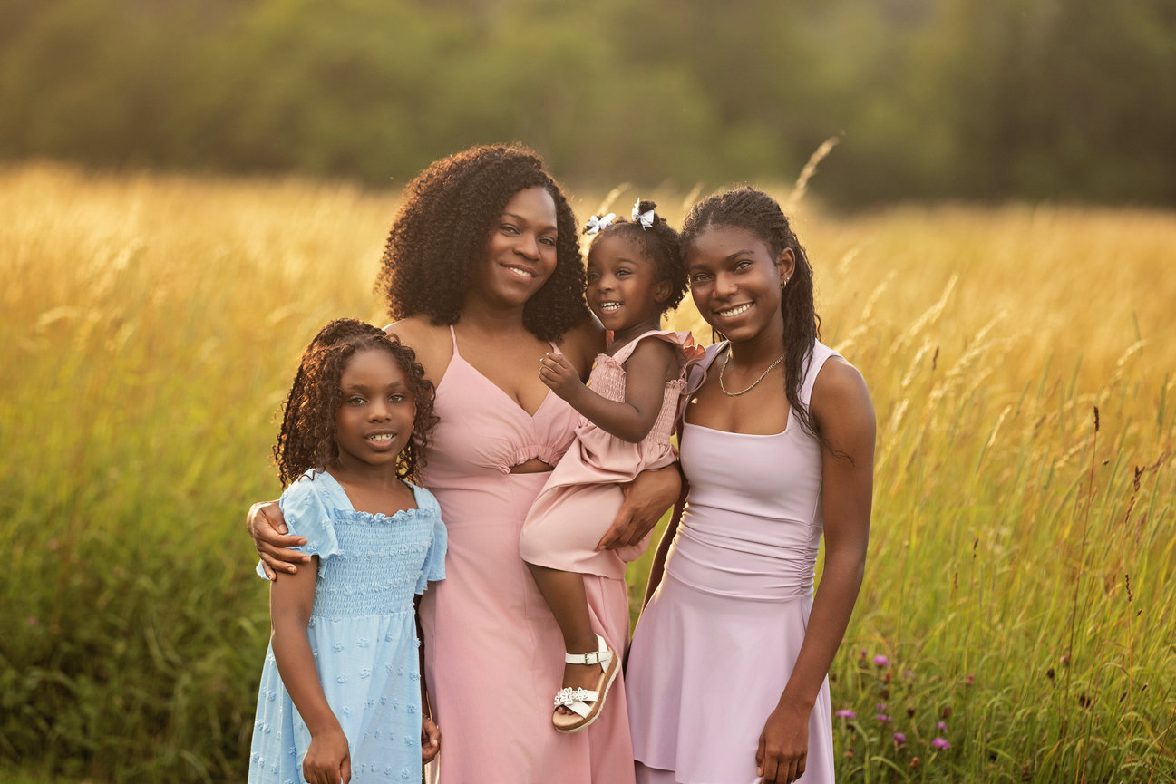 Mother with three daughters standing together in a sunlit meadow