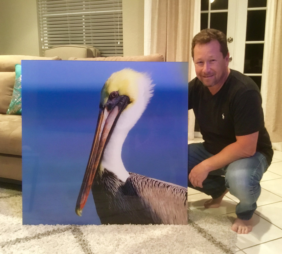 Photographer posing with a pelican painting in a living room