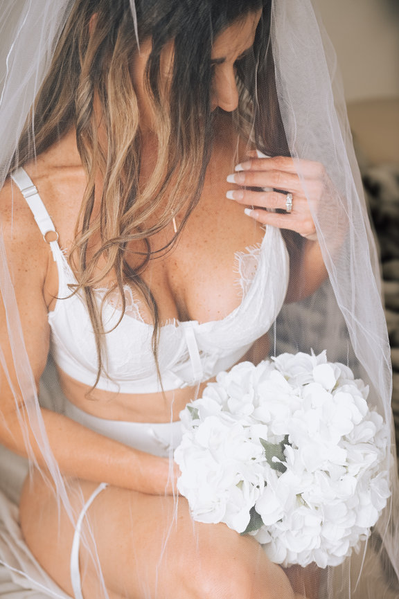 Elegant bridal boudoir session with bride wearing a white veil, showcasing her wedding ring and bouquet in Meridian Boise Idaho