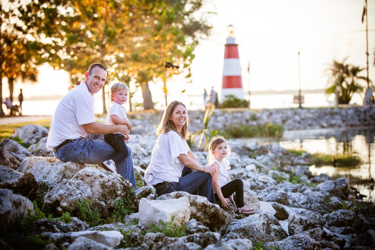 Family sitting on rocks near a lighthouse