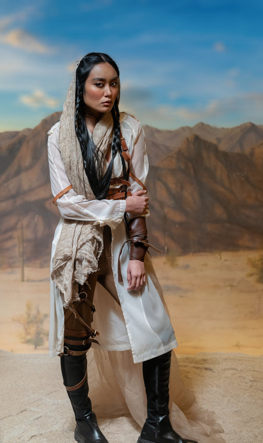 Model in desert fashion standing against a mountainous backdrop