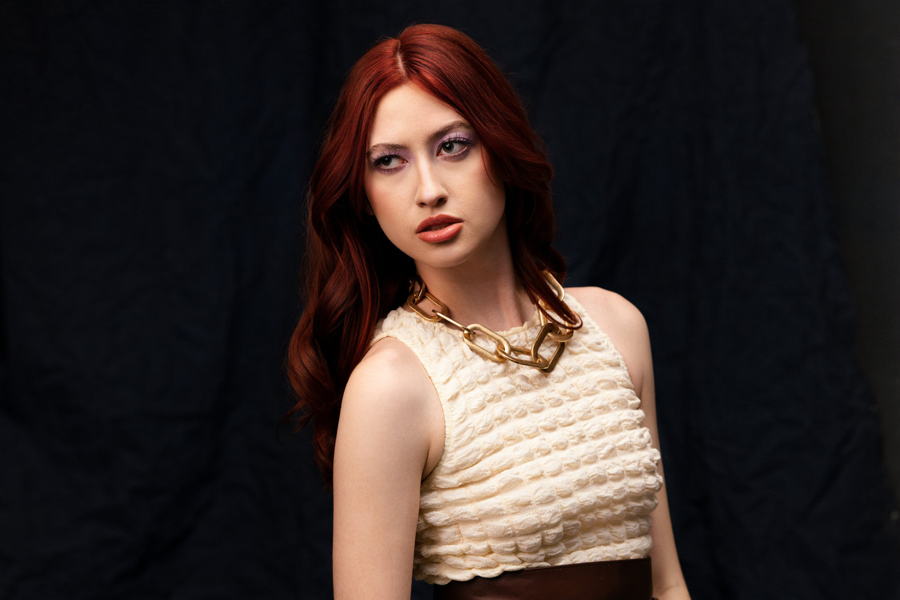 Model with striking red hair posing against a dark backdrop