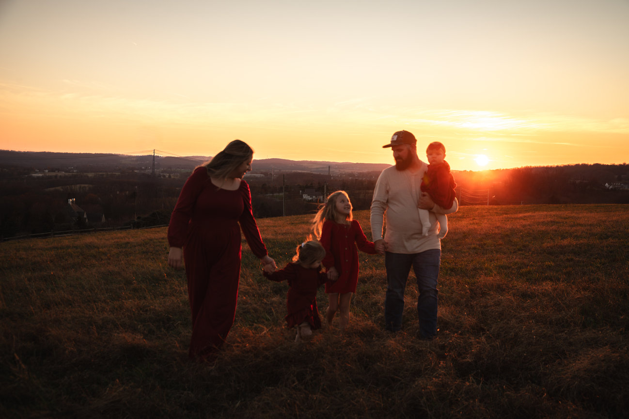 Family walking in a field at sunset