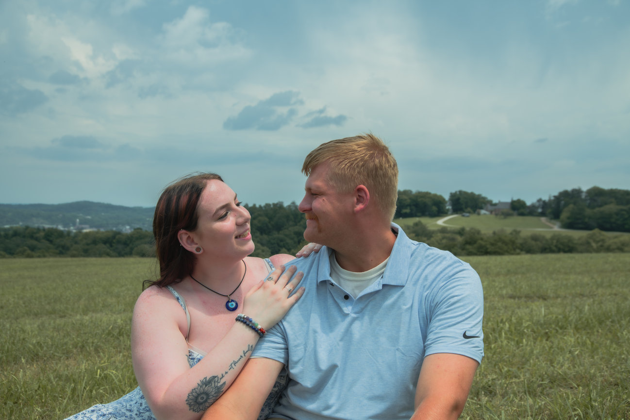 Couple sitting in a field looking at each other